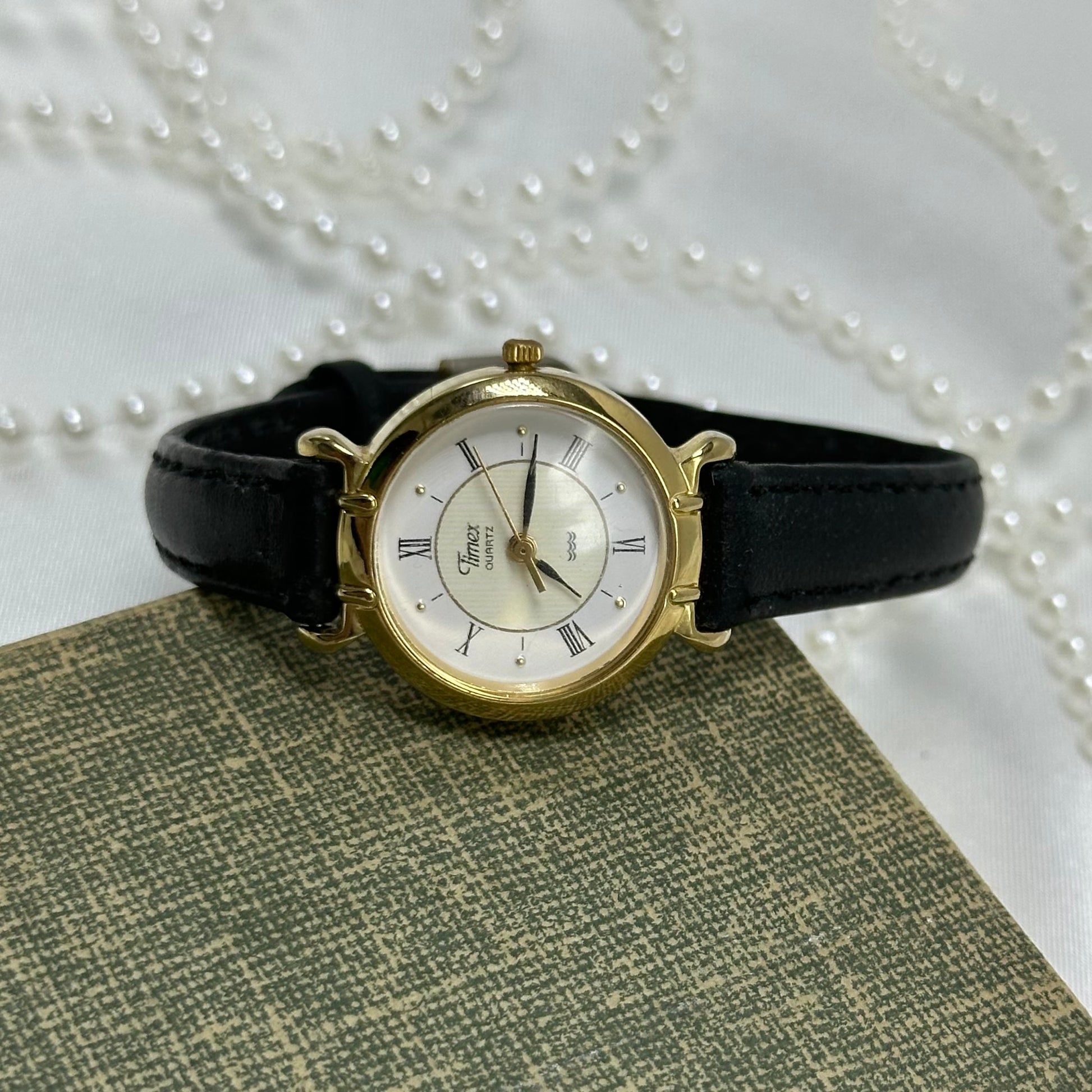 Gold tone Timex round dial watch with black leather band and quartz movement. Water resistant.