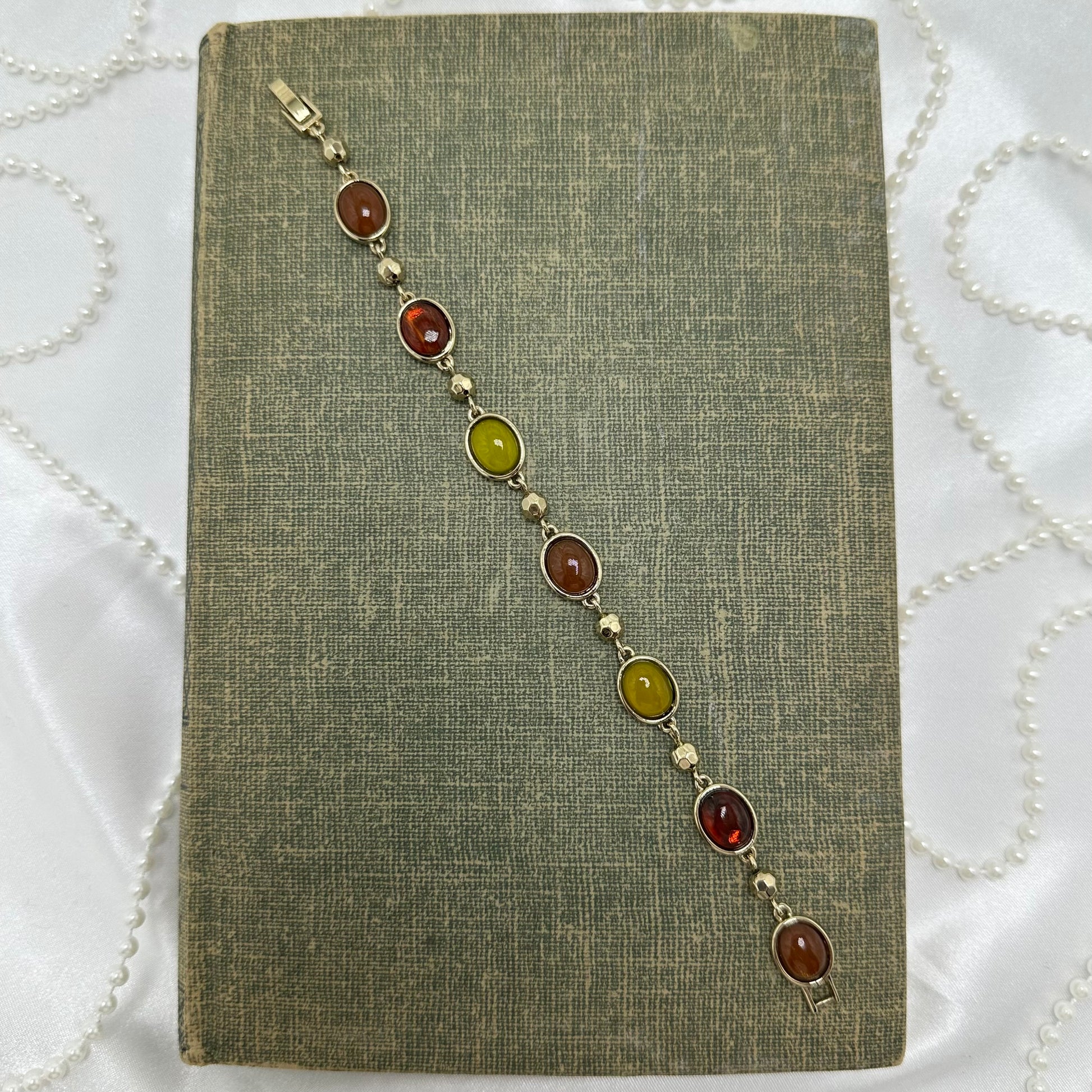 Gold tone bracelet with yellow, amber, and red gemstones.