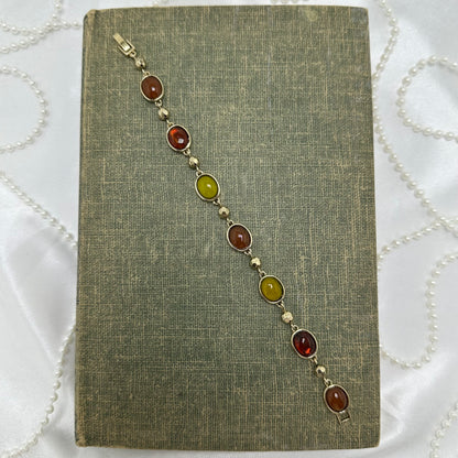 Gold tone bracelet with yellow, amber, and red gemstones.