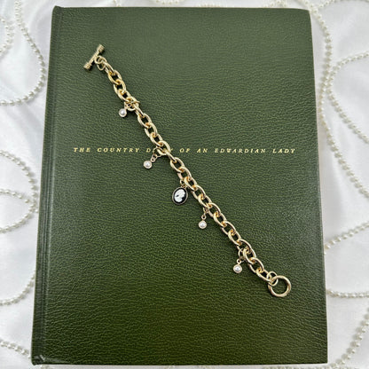 Gold tone chunky chain charm bracelet with faux pearls, black cameo, and t-bar style clasp.