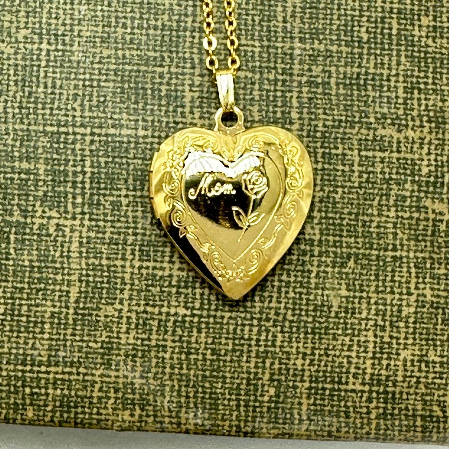 Gold tone heart locket with "Mom" and floral details engraved.