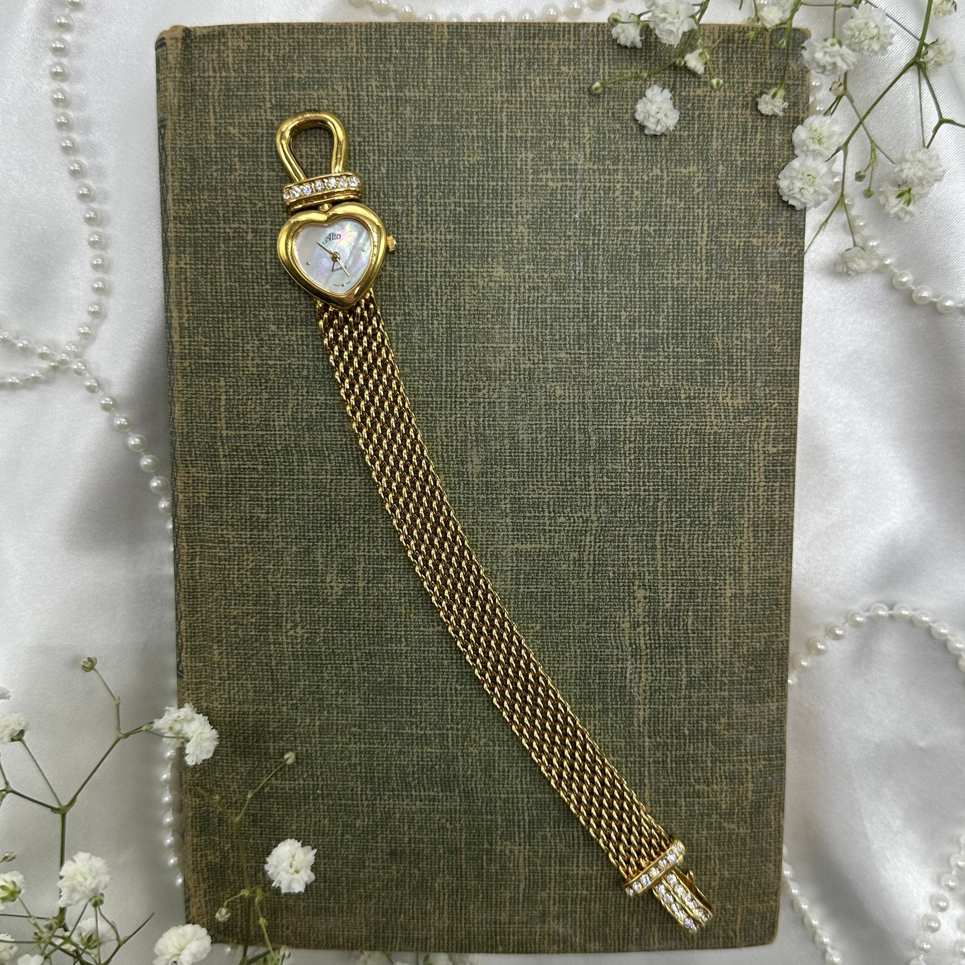 Gold tone mother of pearl heart dial Alto watch with quartz movement and hook clasp.