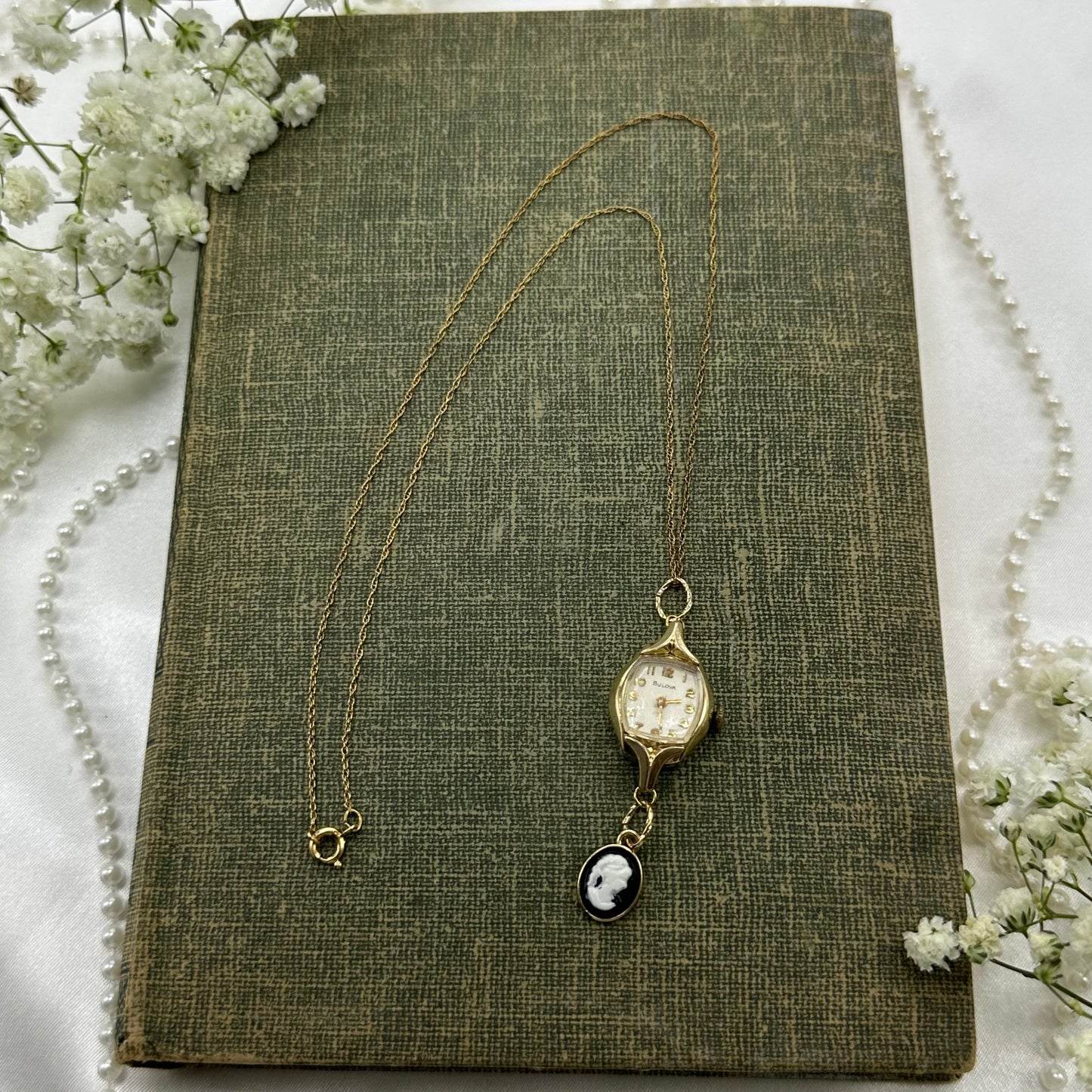 Gold tone necklace with vintage 1962 10k RGP Bulova watch and black cameo pendant.
