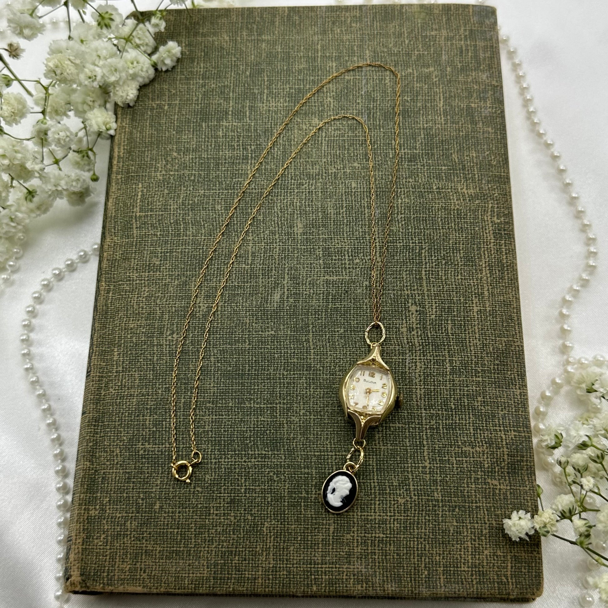 Gold tone necklace with vintage 1962 10k RGP Bulova watch and black cameo pendant.
