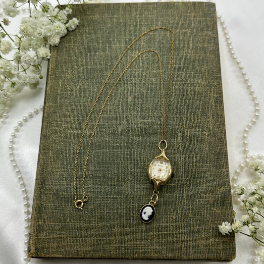 Gold tone necklace with vintage 1962 10k RGP Bulova watch and black cameo pendant.