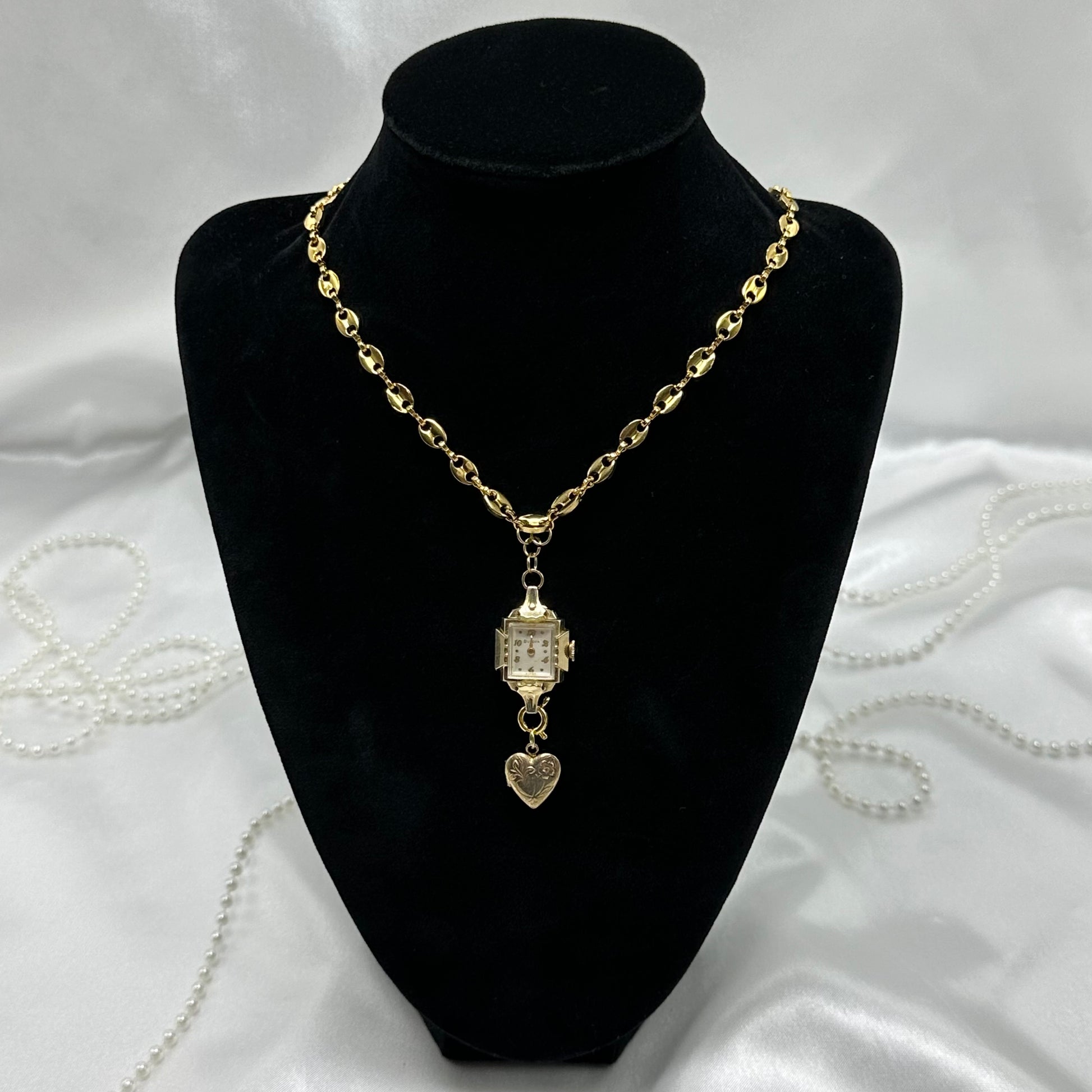 Gold tone necklace with vintage watch and heart locket pendant.