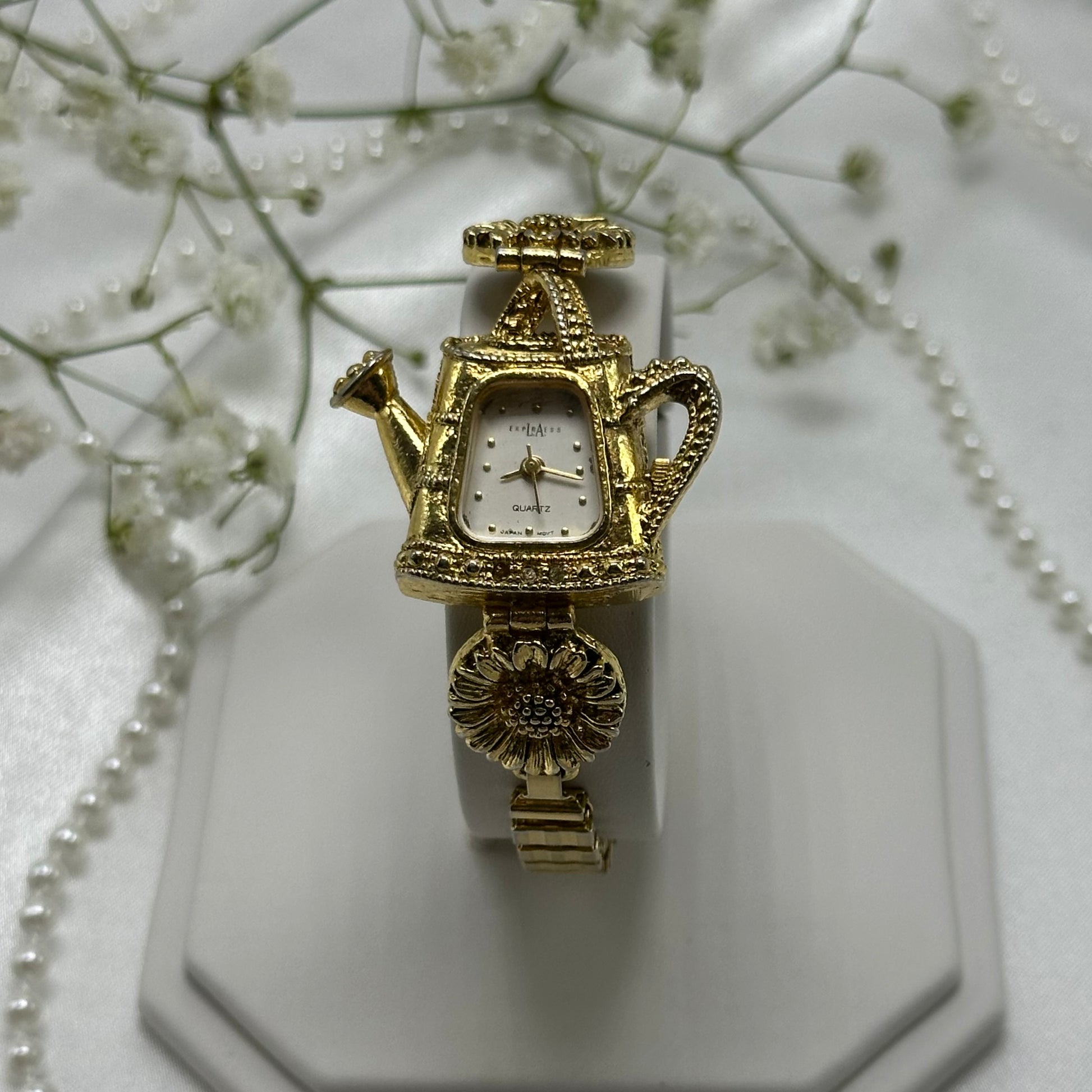 Gold tone sunflowers and watering can LA Express watch with quartz movement and stretchable band.
