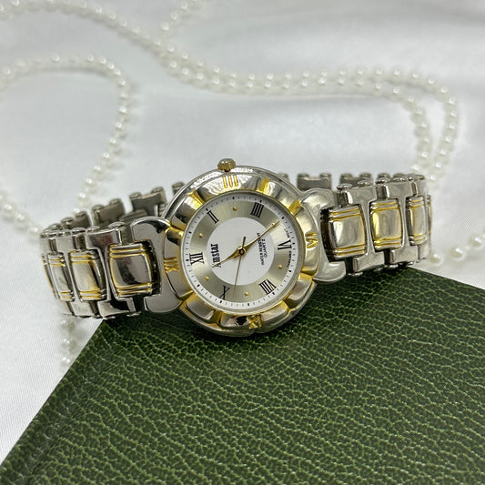 Silver and gold tone Amstar tank watch with round dial and roman numeral markers.