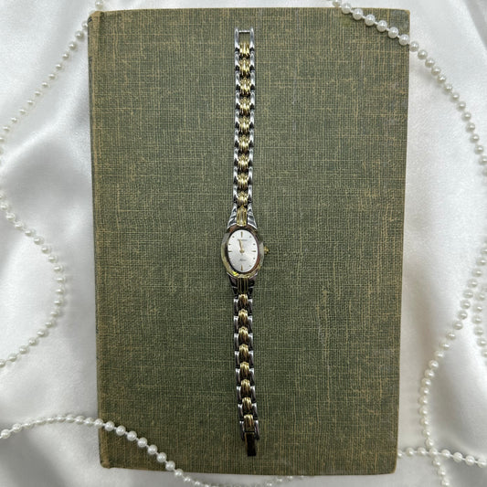 Silver and gold tone Armitron watch with crystal bezel and clasp band.