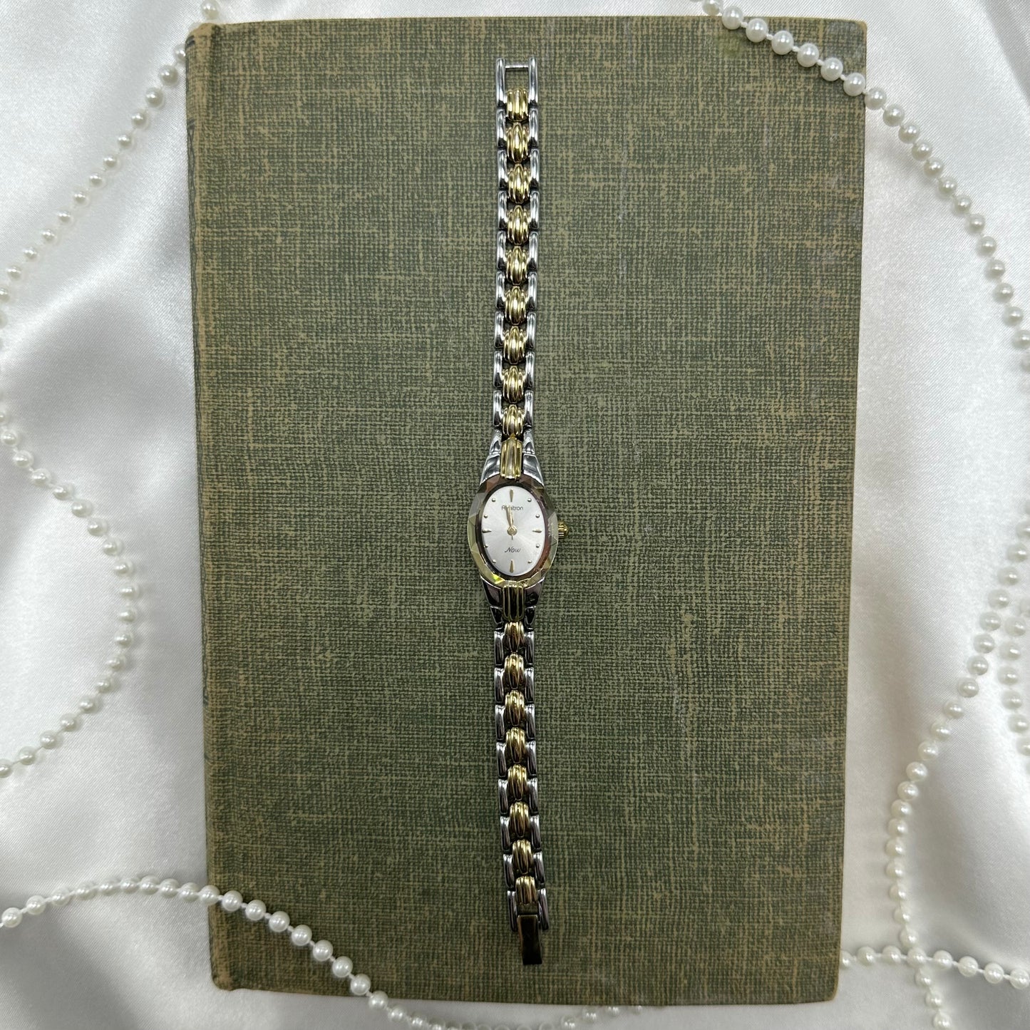 Silver and gold tone Armitron watch with crystal bezel and clasp band.