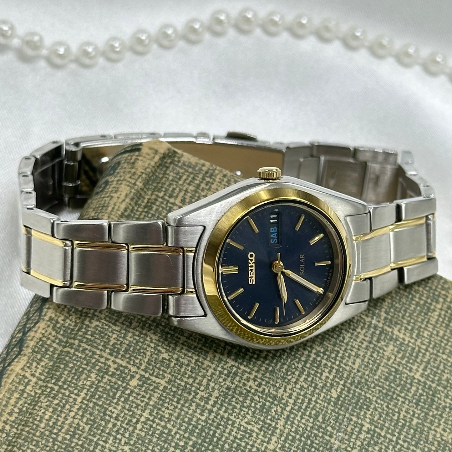 Silver and gold tone Solar Seiko watch with navy blue dial and date display.
