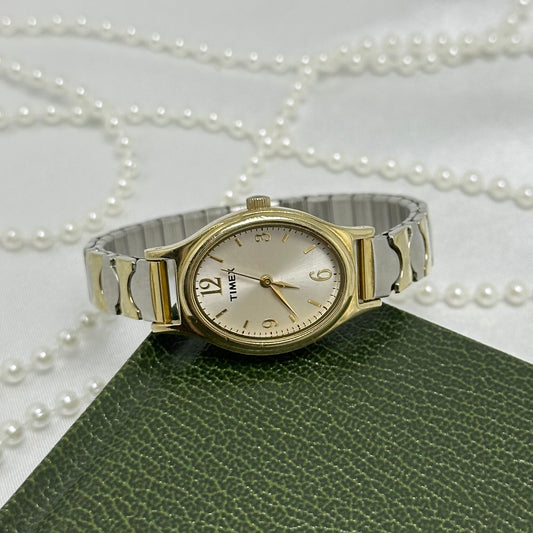 Silver and gold tone Timex watch with oval dial and stretchable band.