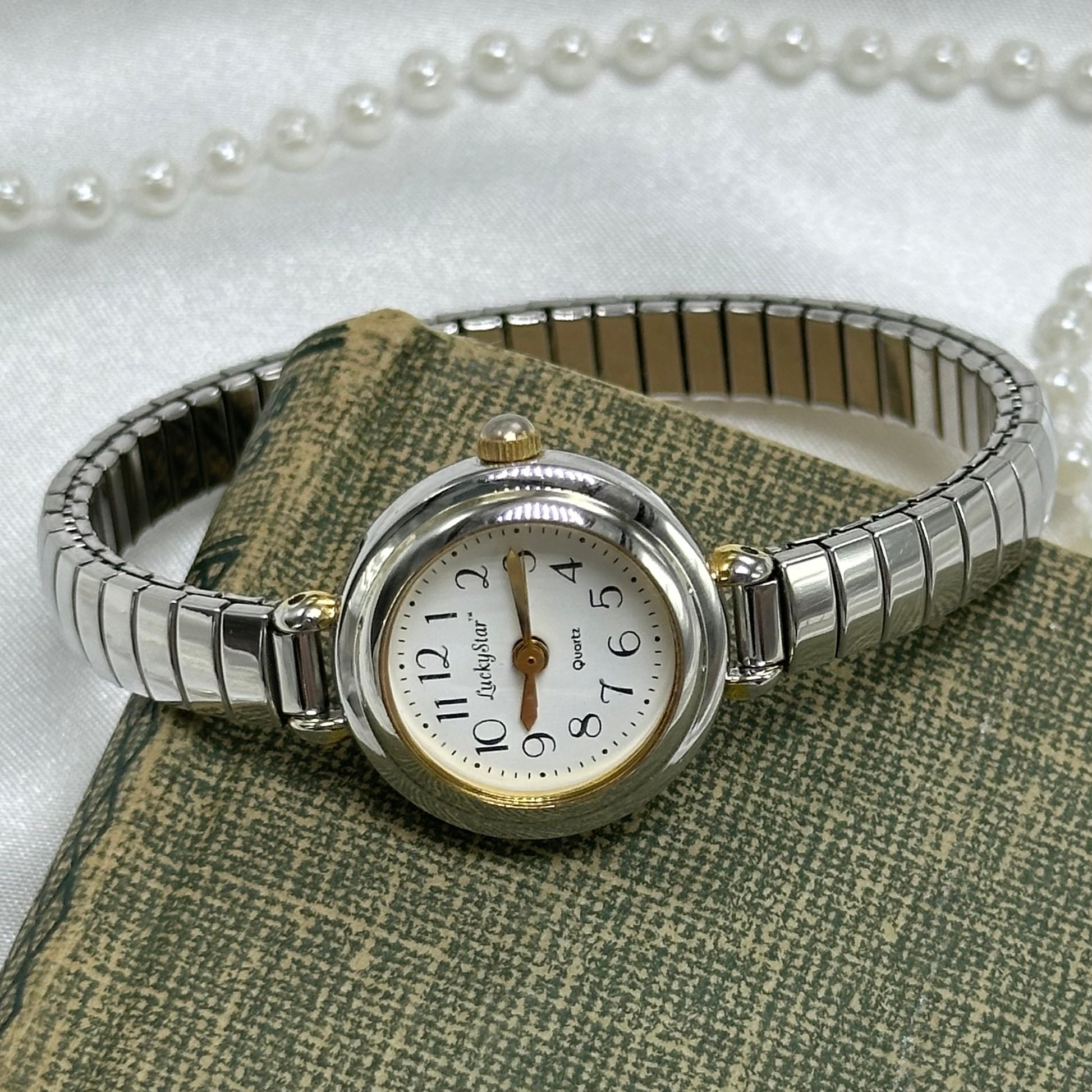 Silver and gold tone bubble dial Lucky Star watch with stretchable band and quartz movement.