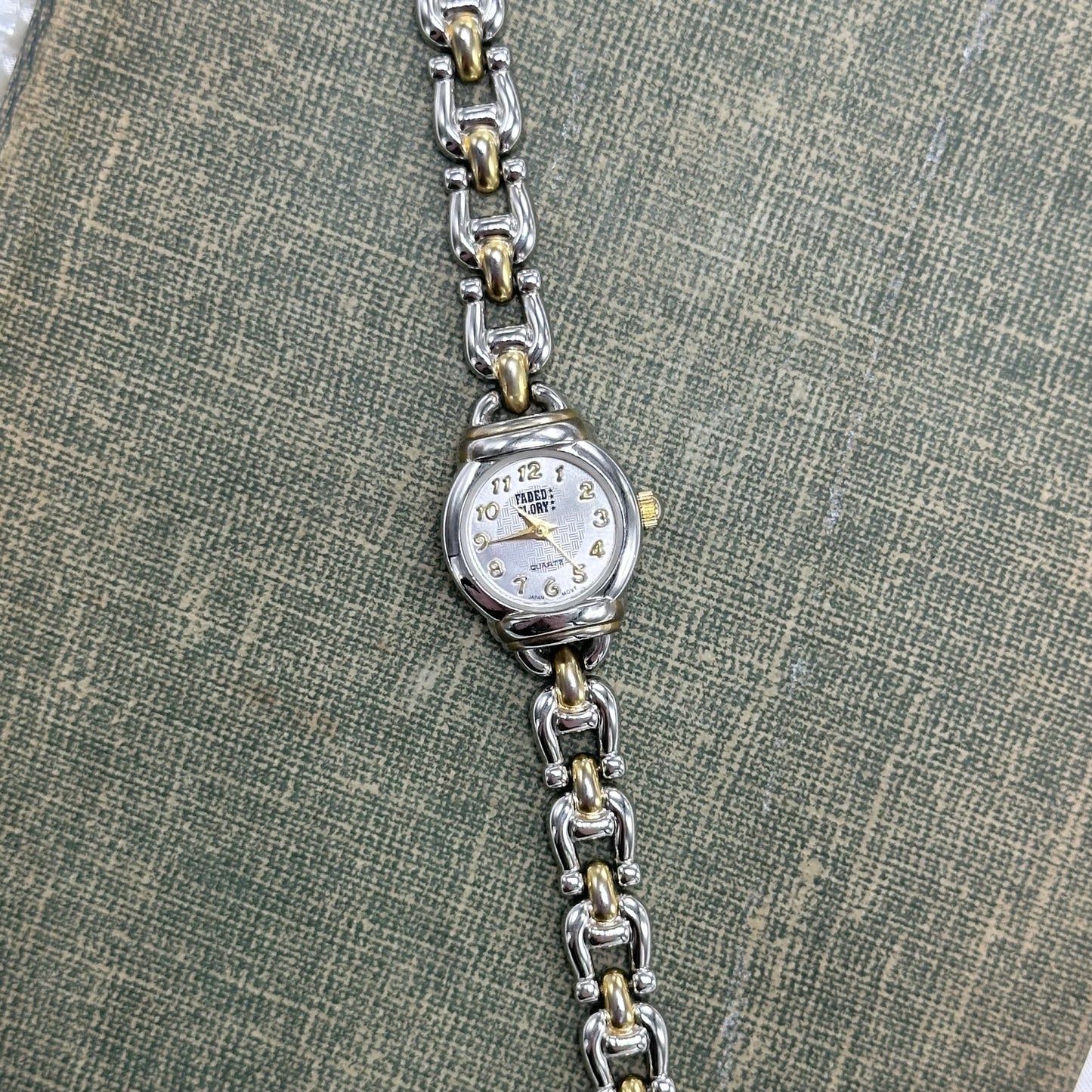Silver and gold tone round dial Faded Glory watch with dainty chain clasp band and quartz movement.