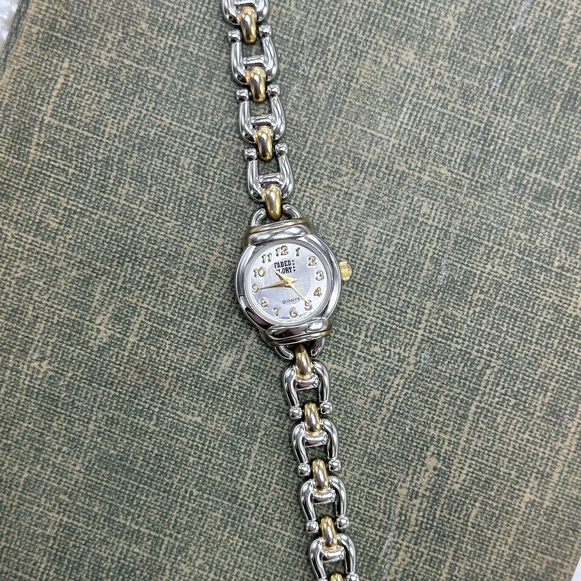Silver and gold tone round dial Faded Glory watch with dainty chain clasp band and quartz movement.