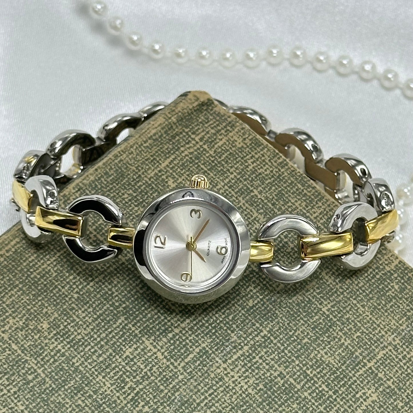 Silver and gold tone round dial Prima Dona watch with unique chain link clasp band.