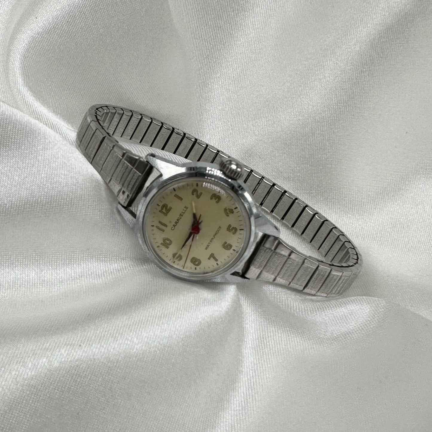 Silver tone Caravelle waterproof manual winding women's watch with stretchable band and glow in the dark dial from 1968