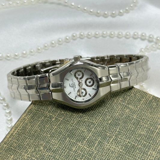 Silver tone Contemplate watch with unique calendar display dial and double locking fold over clasp. Band still has protective plastic cover.
