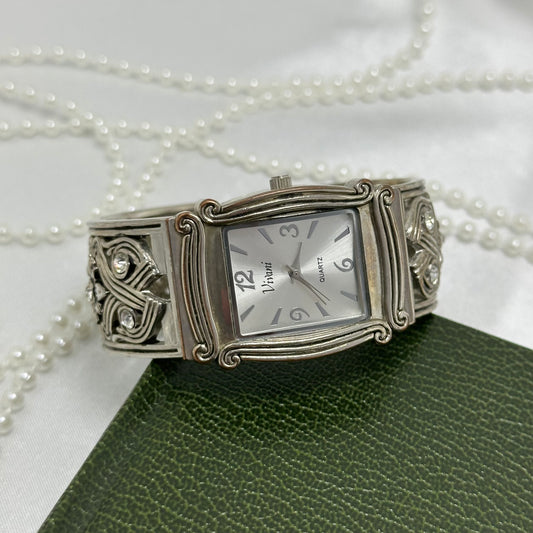 Silver tone Vivani cuff watch with square dial and detailed crossed diamanté band.