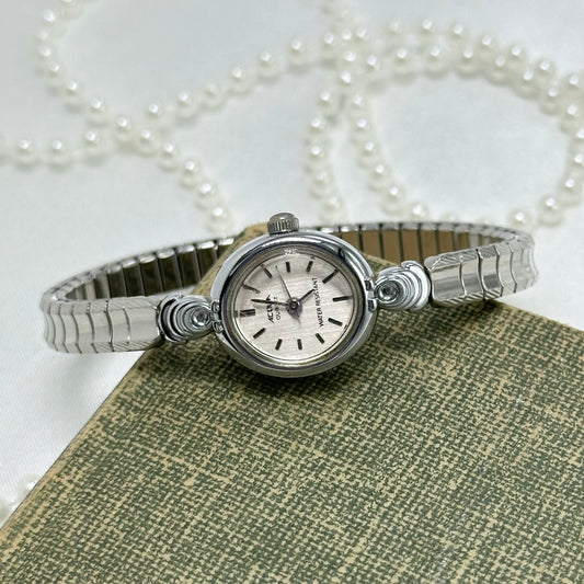 Silver tone round dial Acqua watch with quartz movement and stretchable band. Water Resistant.