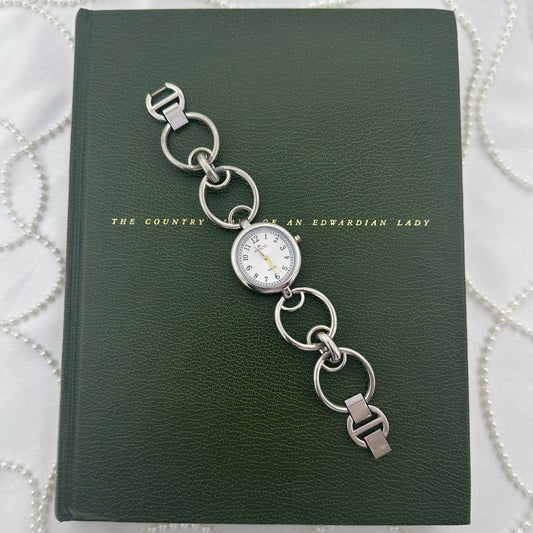 Silver tone round dial Minicci watch with gold hands and crown and circle link band.