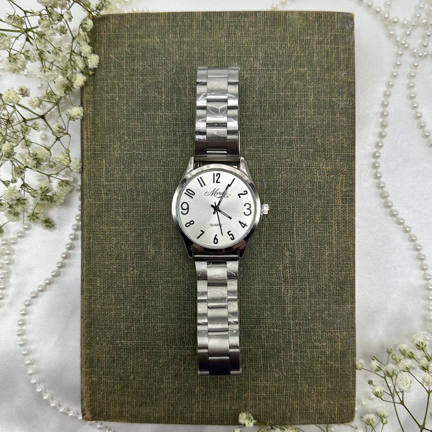 Silver tone round dial Moretti watch with quartz movement and thick clasp band. Band still has original plastic coverings and the plastic was never removed from the crown