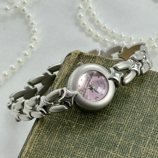 Silver tone watch with pink bubble dial and quartz movement.