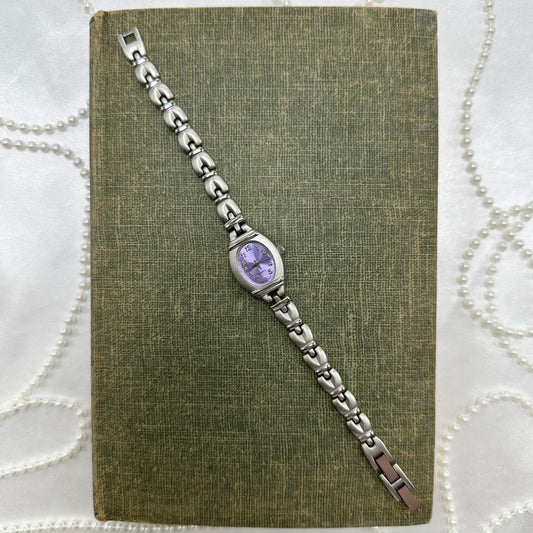 Silver tone watch with purple dial and quartz movement.
