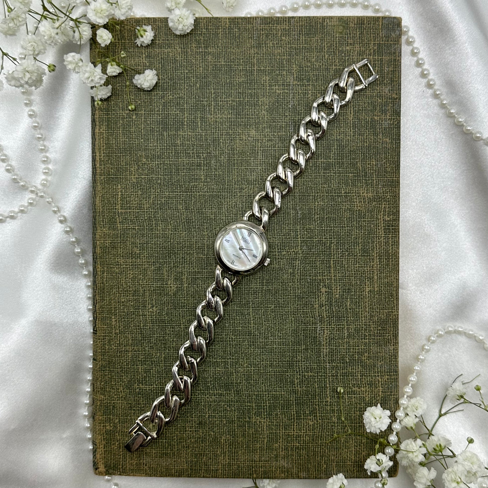 Silver tone watch with quartz movement and chain band. Dial is mother of pearl.