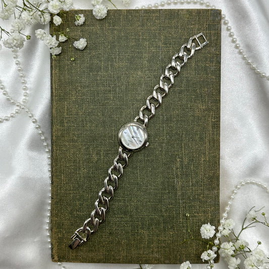 Silver tone watch with quartz movement and chain band. Dial is mother of pearl.