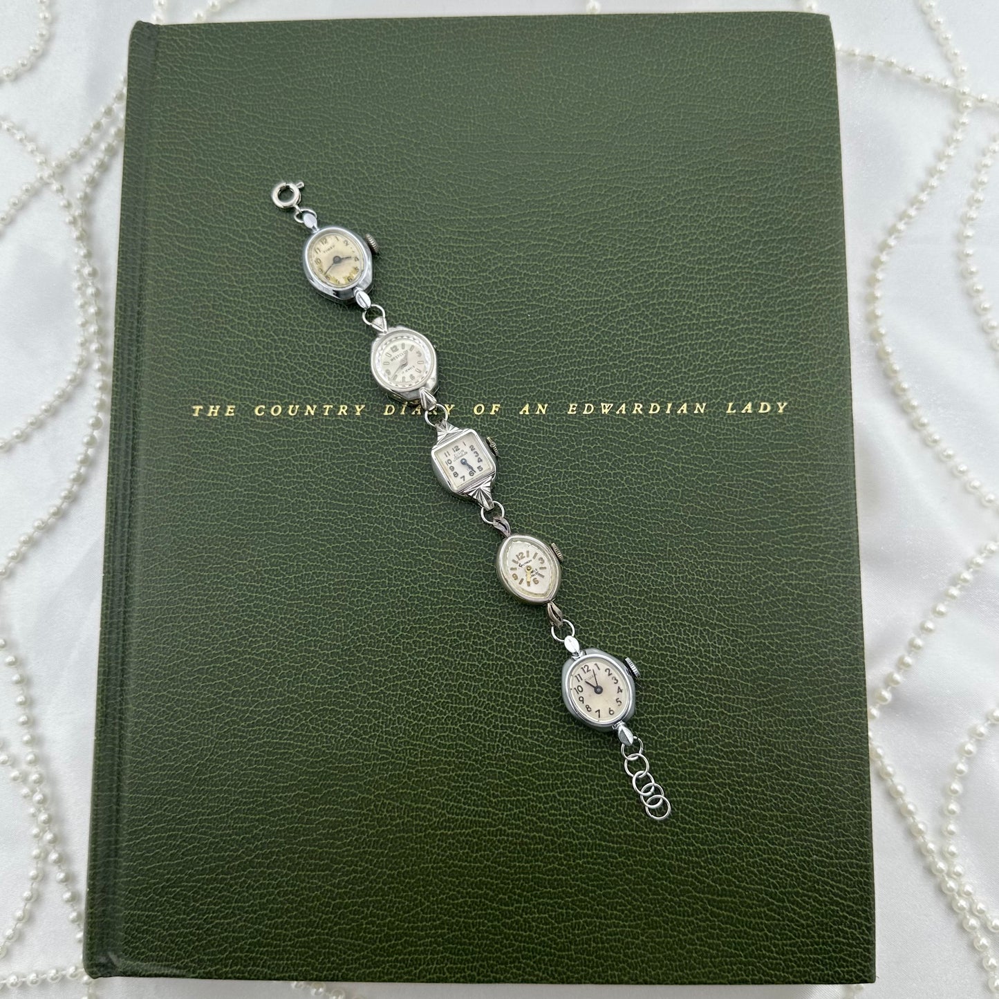 Six vintage silver tone manual winding watches linked with metal hoops to be worn as a bracelet. Watches do not run.