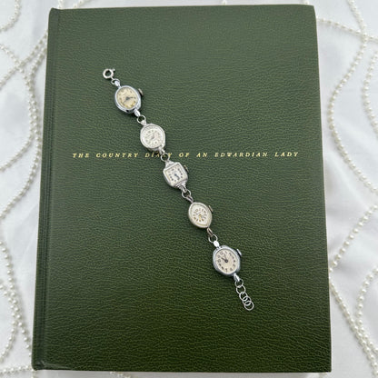 Six vintage silver tone manual winding watches linked with metal hoops to be worn as a bracelet. Watches do not run.