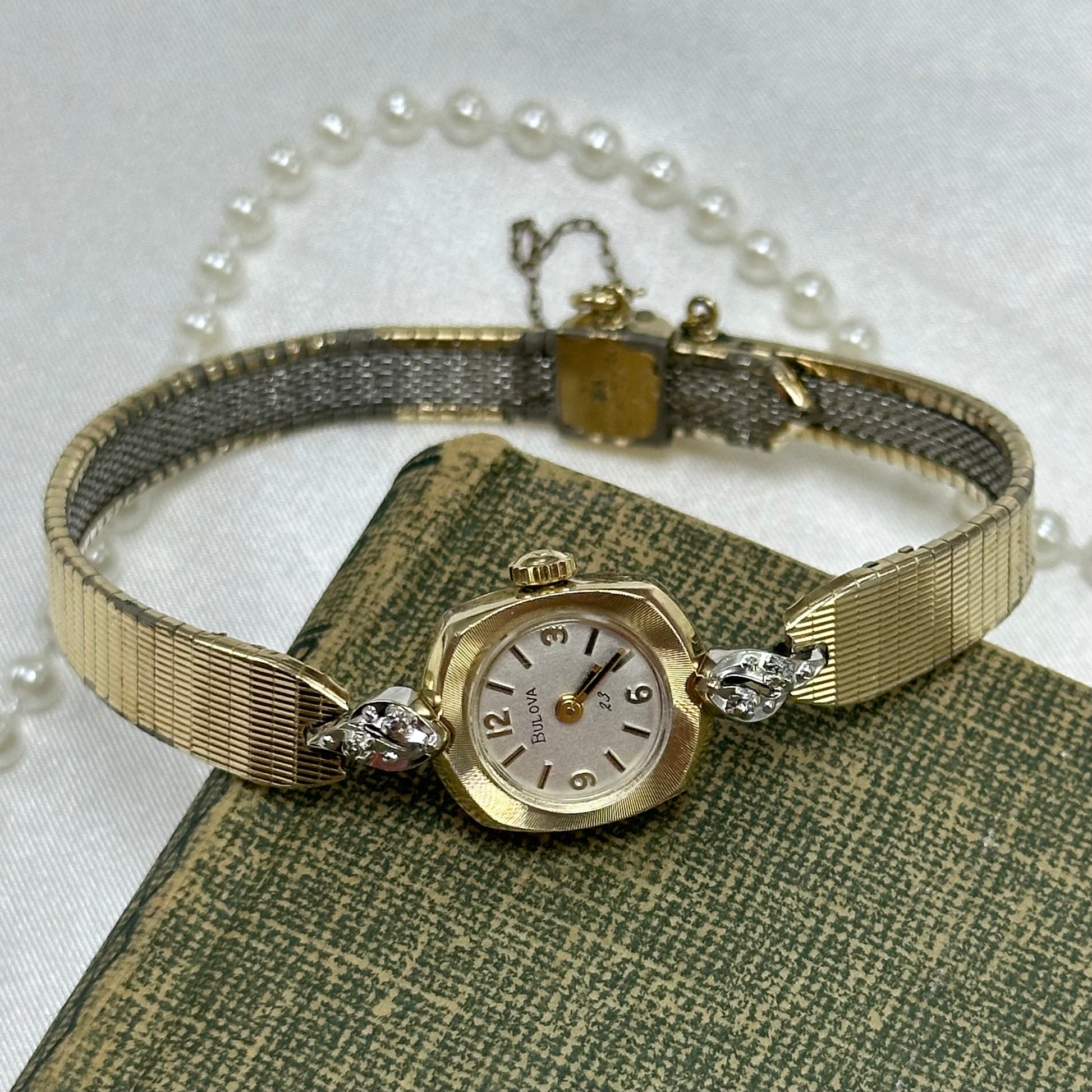 Vintage 10k RGP Bulova 23 jewels manual winding diamanté watch with adjustable metal band and safety chain from the 1970's. Watch comes with original B crown and striking black hands.