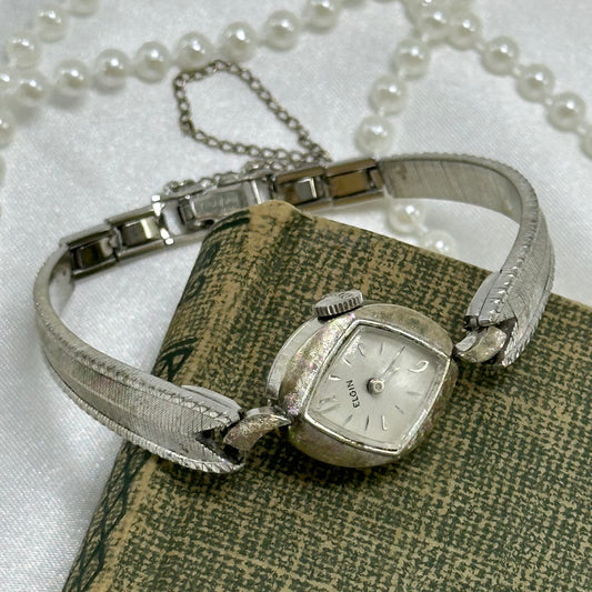 Vintage 10k rolled gold plated dainty Elgin manual winding cocktail watch with textured clasp band and safety chain.