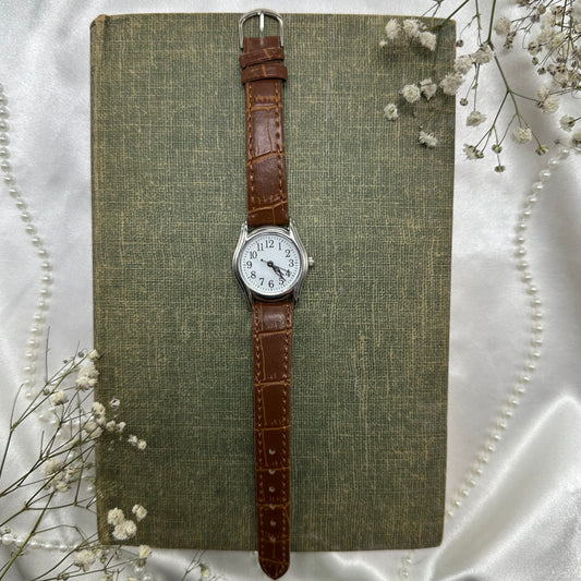 Vintage brown and silver tone watch with brown strap band.
