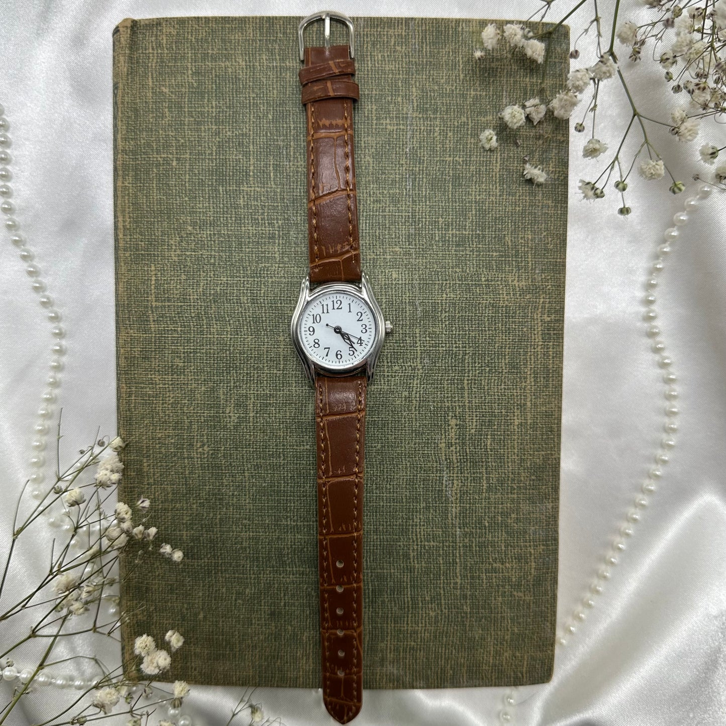 Vintage brown and silver tone watch with brown strap band.