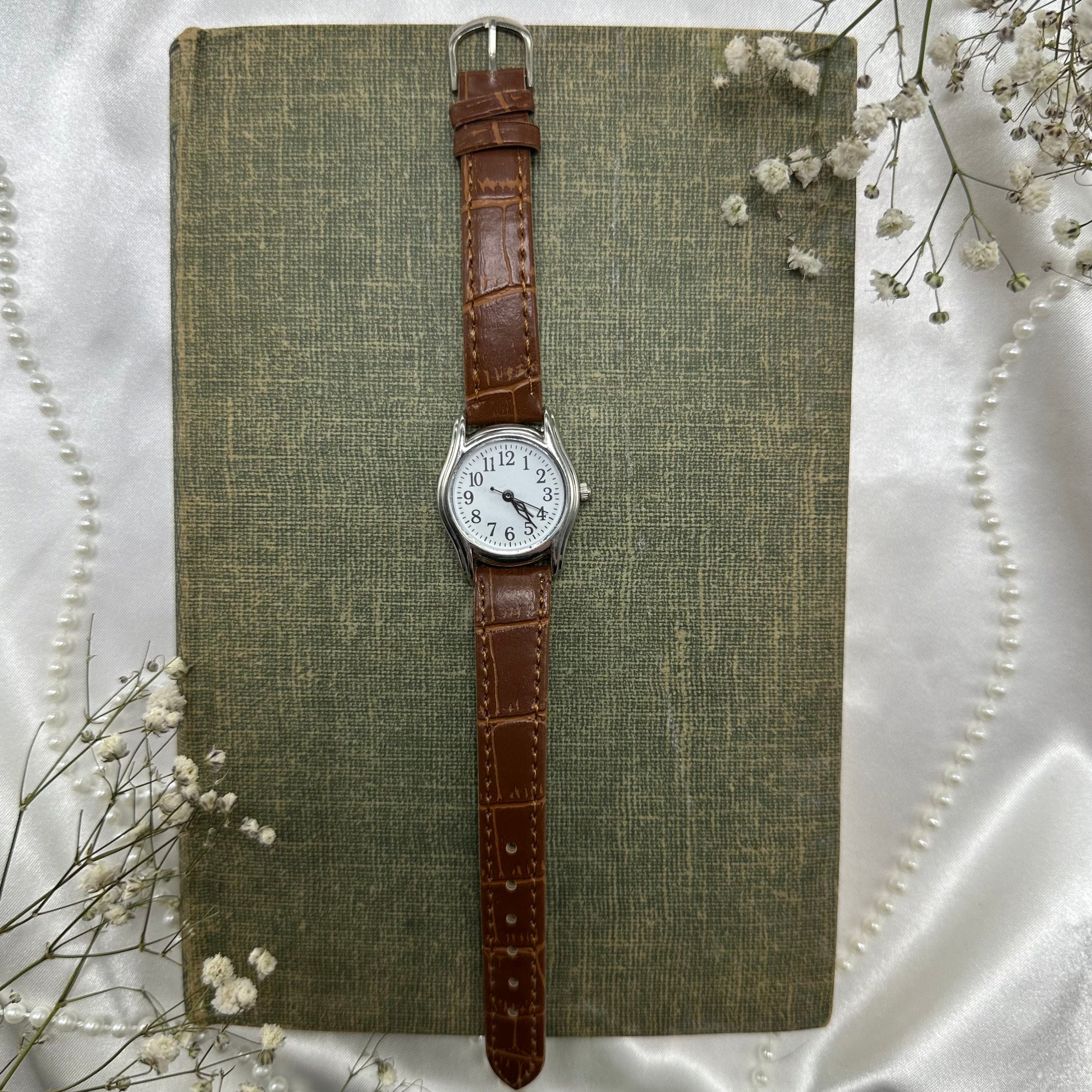 Vintage brown and silver tone watch with brown strap band.