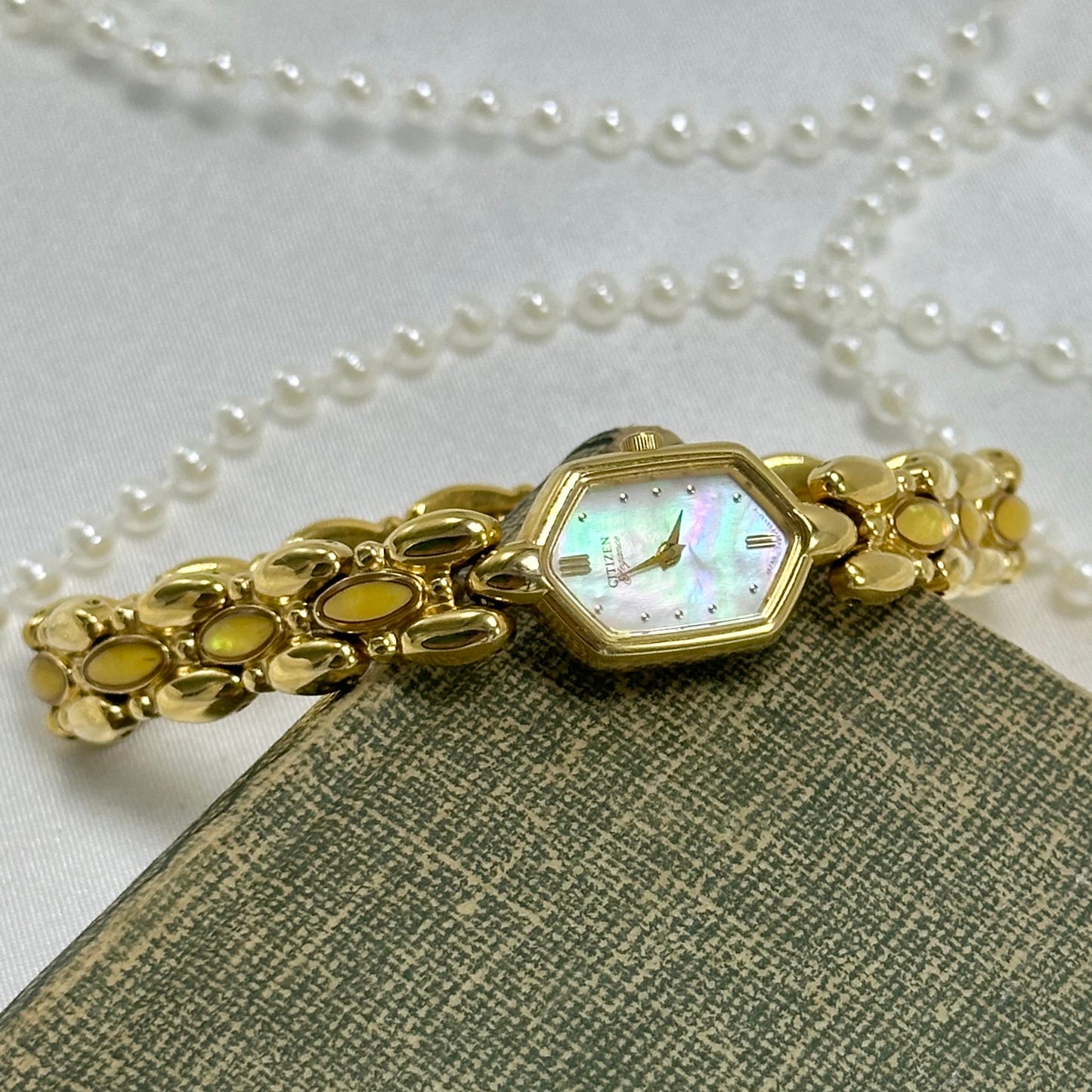 Vintage dainty gold tone Citizen watch with mother of pearl dial and yellow iridescent gemstone band.