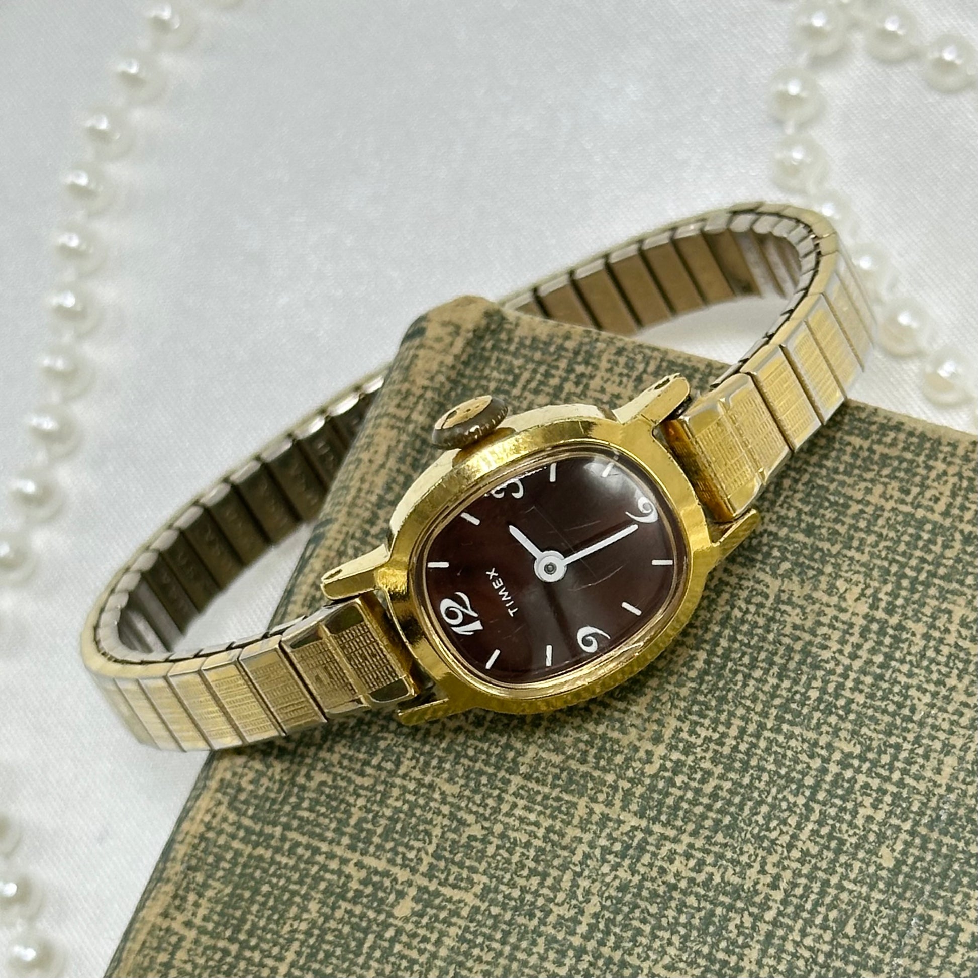 Vintage dainty gold tone Timex manual winding watch with unique brown dial and stretchable band.