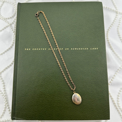 Vintage dainty locket with engraved floral design.