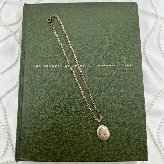 Vintage dainty locket with engraved floral design.