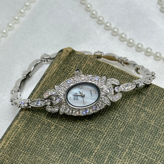 Vintage elegant diamanté Nolan Miller silver tone watch with blue jewel crown and mother of pearl dial.