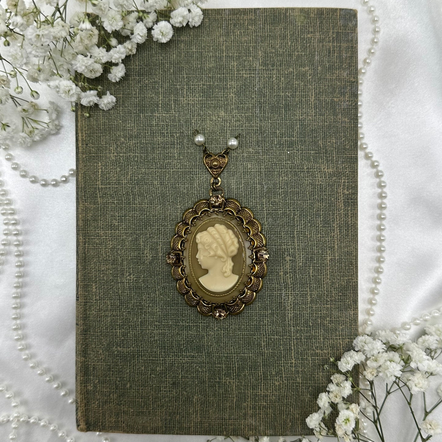 Vintage filigree oval hanging cameo pendant with gemstones and pearls.