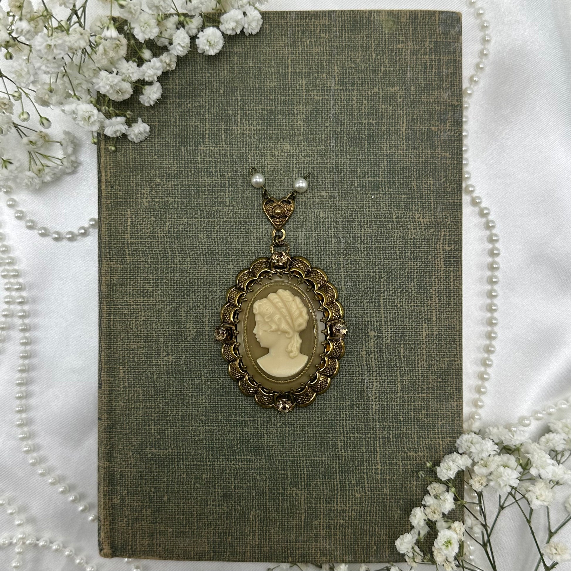 Vintage filigree oval hanging cameo pendant with gemstones and pearls.