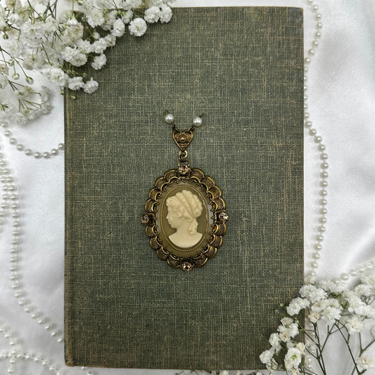 Vintage filigree oval hanging cameo pendant with gemstones and pearls.