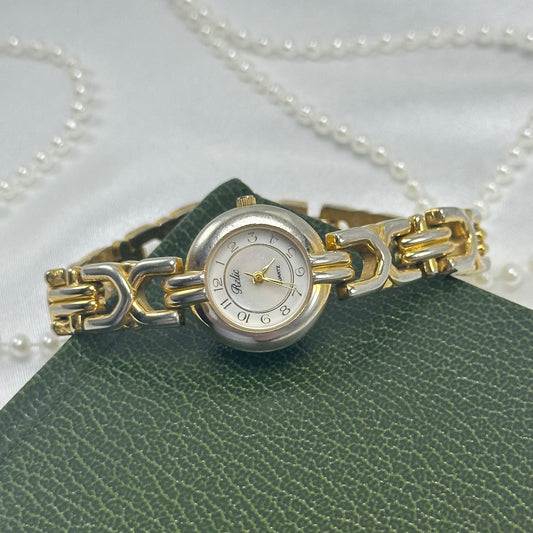 Vintage gold and silver tone Relic watch with round mother of pearl dial and metal clasp band.
