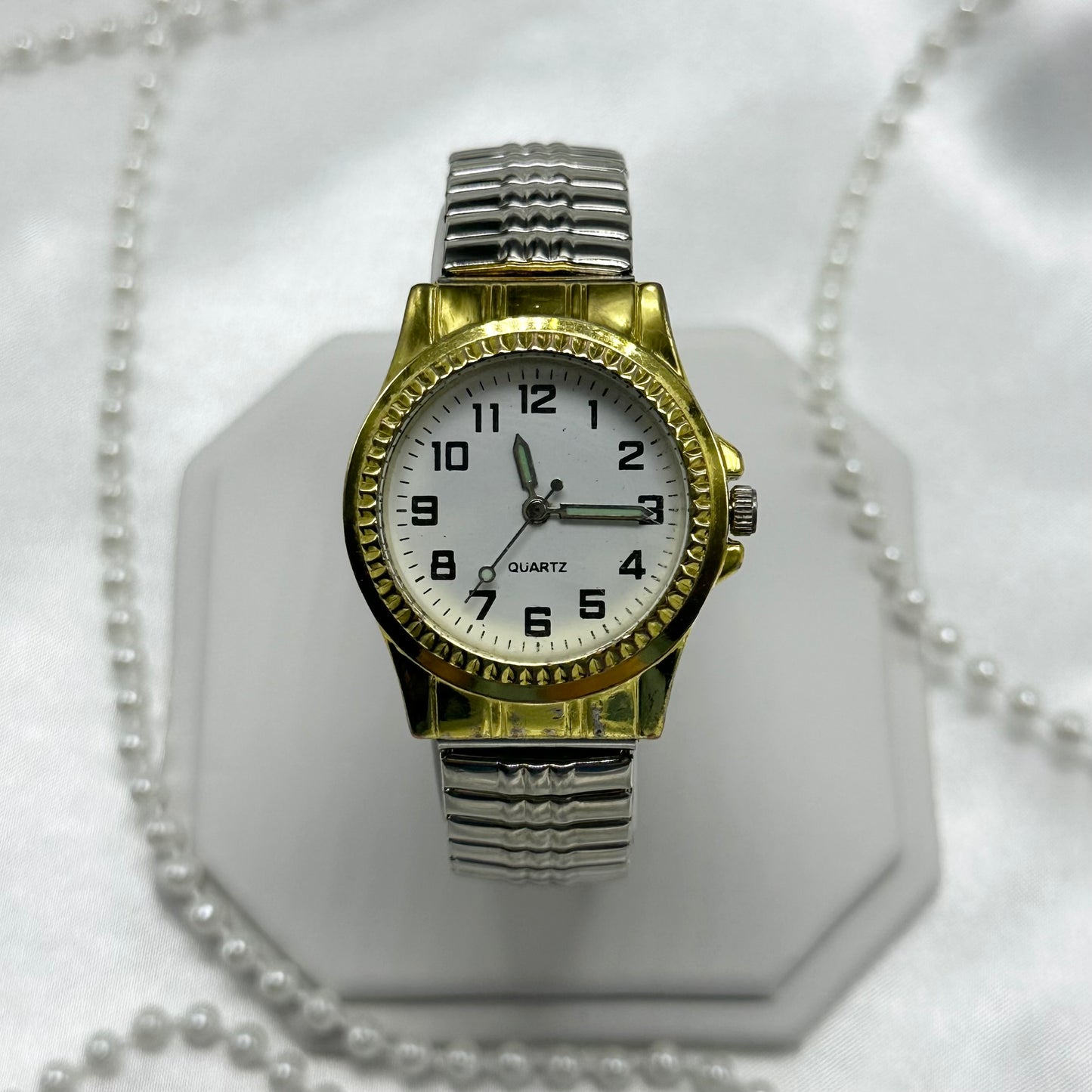 Vintage gold and silver tone watch with quartz movement and stretchable band.