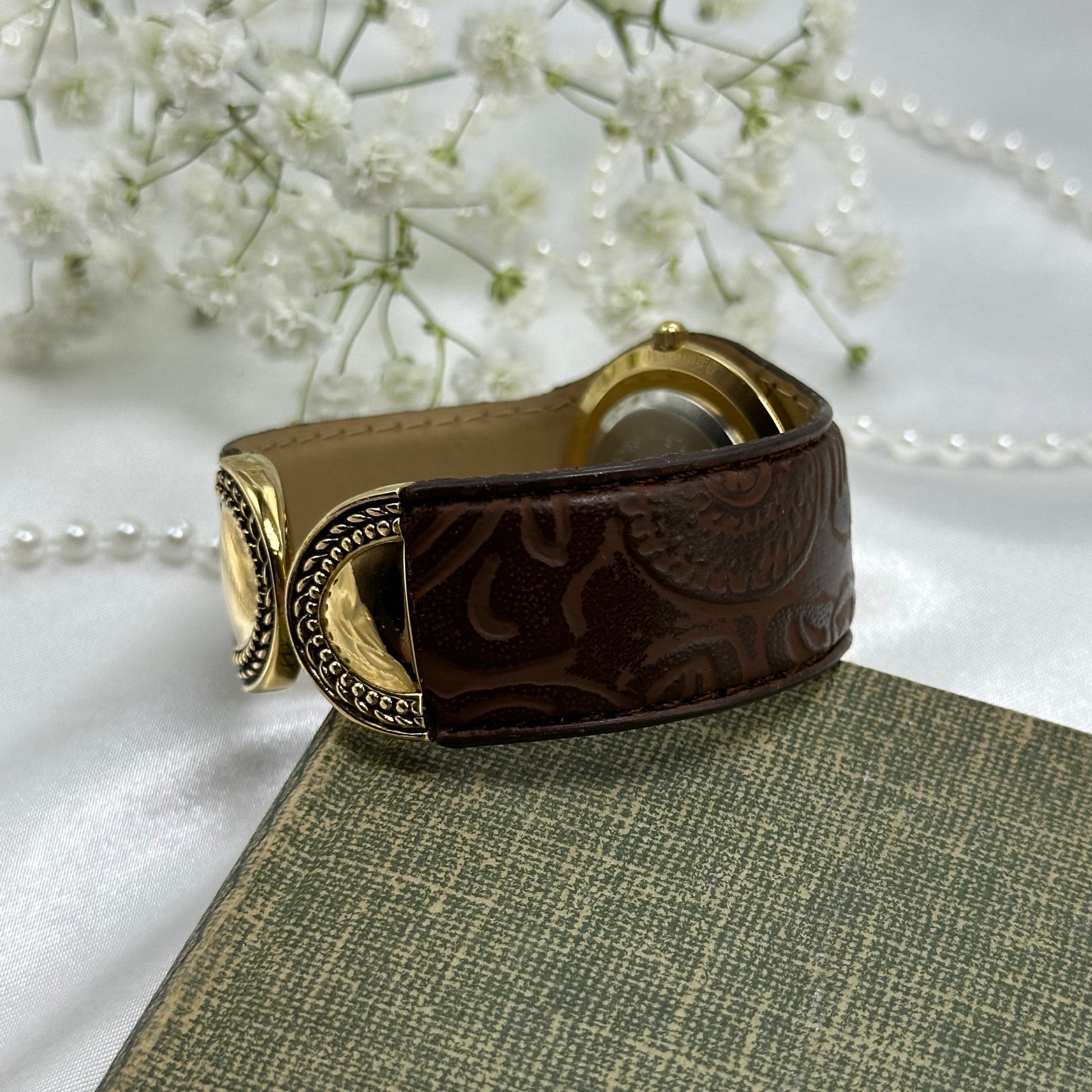 Vintage gold tone Avon cuff watch with brown leather band and quartz