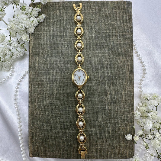Vintage gold tone Avon watch with quartz movement and faux pearl clasp band.