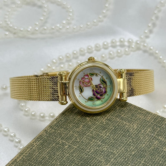 Vintage gold tone Avon watch with round flower dial and quartz movement.